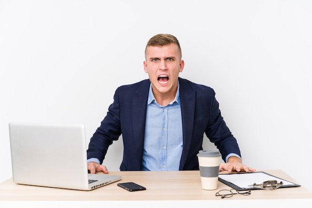 Foto homem de negócios jovem com um laptop, gritando muito irritado e agressivo.