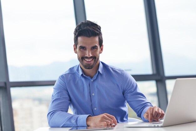 homem de negócios jovem feliz trabalha no escritório moderno no computador