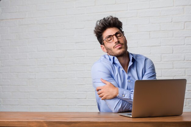 Homem de negócios jovem sentado e trabalhando em um laptop orgulhoso e confiante, apontando os dedos