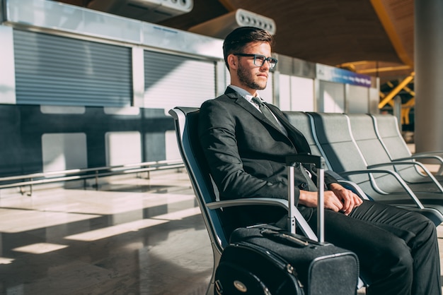 Foto homem de negócios jovem sentado no aeroporto esperando o voo