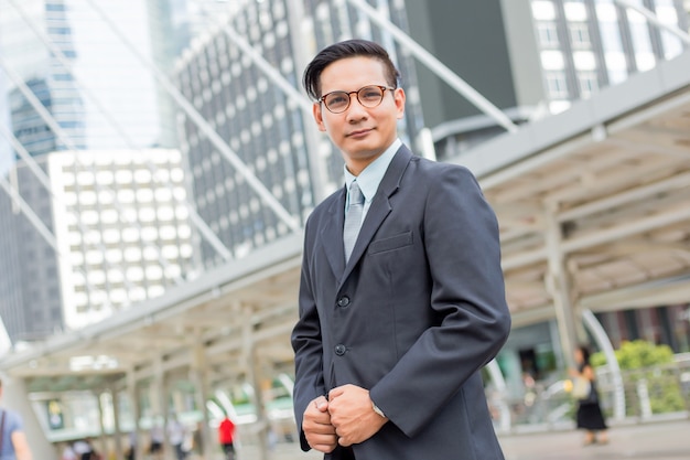 Homem de negócios jovem Ásia na frente do edifício moderno no centro da cidade Conceito de jovens empresários