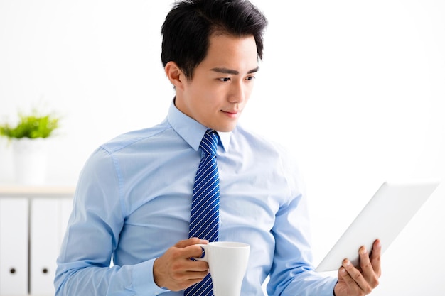 Homem de negócios jovem sorridente lendo o tablet