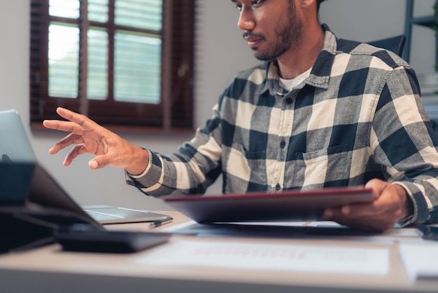 Homem de negócios lê documento de negócios para verificar relatório financeiro e contábil no laptop no escritório