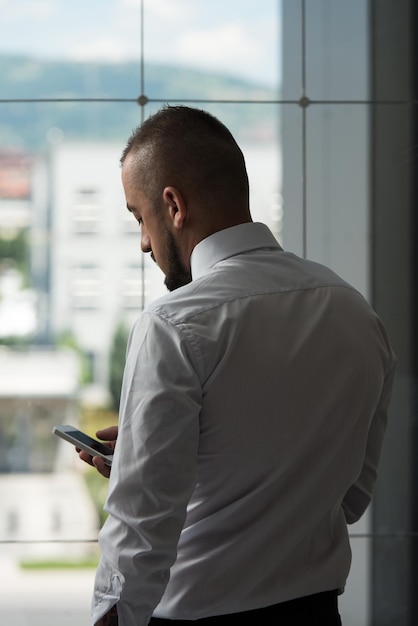 Homem de negócios lendo mensagem de texto em um celular em um escritório moderno