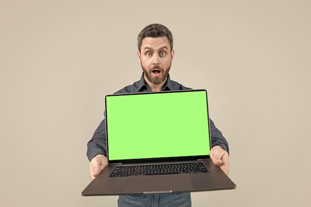 Homem de negócios maduro chocado apresentando computador mostrando sua tela verde para webinar de espaço de cópia