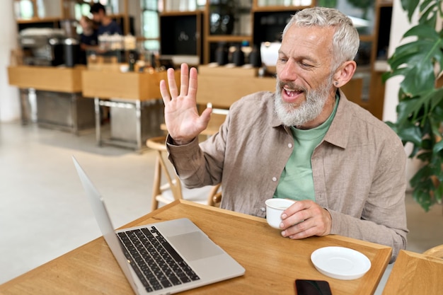 Homem de negócios mais velho feliz usando computador portátil trabalhando remotamente por chamada de vídeo