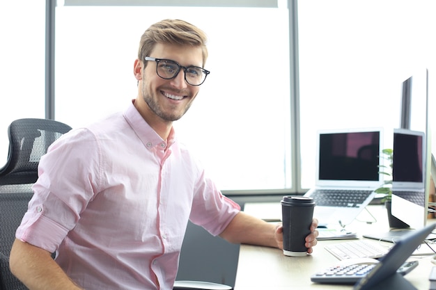 Homem de negócios moderno jovem trabalhando usando tablet digital enquanto está sentado no escritório.