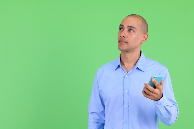 Homem de negócios multiétnico careca bonito contra parede verde