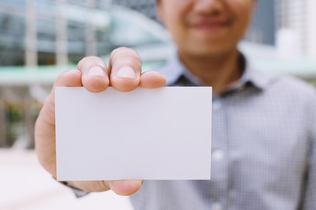 Homem de negócios na mão segure show cartão branco em branco simulado com cantos arredondados.