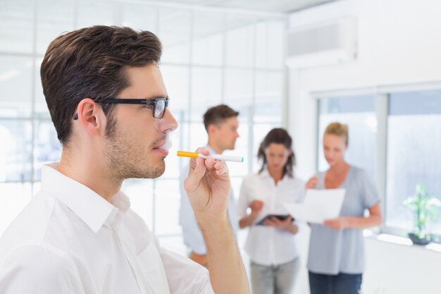 Homem de negócios ocasional que fuma um cigarro eletrônico