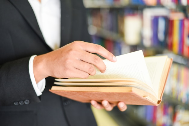 Homem de negócios ou estudante segurando um livro na mão - homem de negócios educação estudo conceito livro de leitura com estante na biblioteca