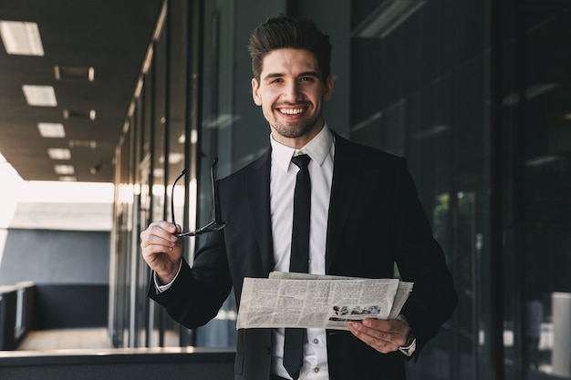 Homem de negócios perto do centro de negócios, segurando a leitura do jornal.