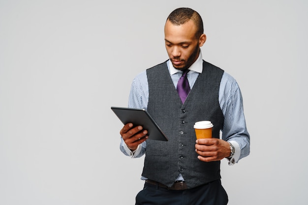 Homem de negócios profissional afro-americano segurando o tablet pc e café.