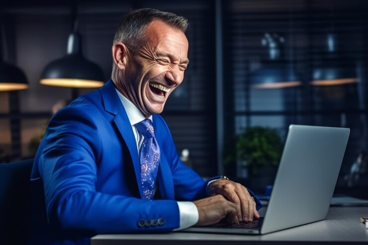 Homem de negócios profissional de meia-idade vestindo terno azul sentado em uma mesa no escritório trabalhando em um laptop