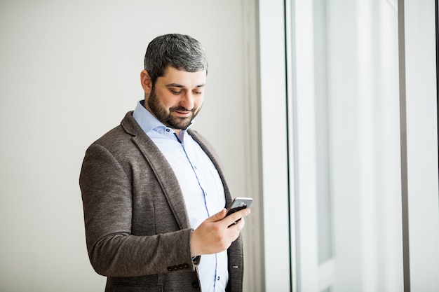 Homem de negócios profissional urbano casual texting celular feliz dentro do escritório banner panorama