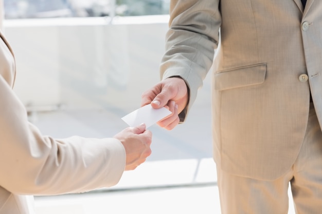 Homem de negócios que passa o cartão para empresária