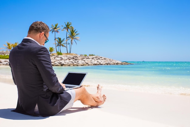 Homem de negócios que trabalha com laptop na praia