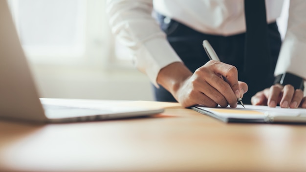 Homem de negócios que trabalha no escritório com sinal um original e portátil. Conceito de negócios modernos.