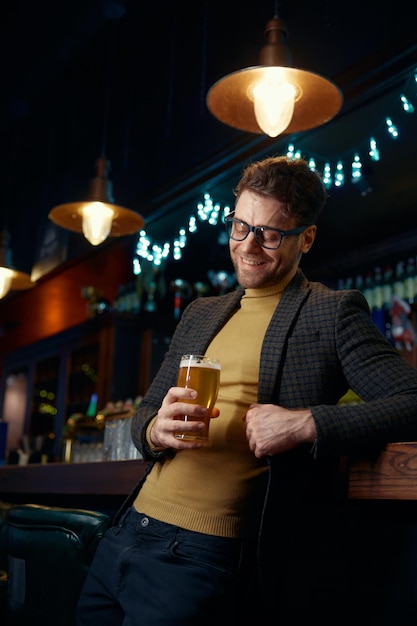 Homem de negócios relaxado com um copo de cerveja espumosa no bar