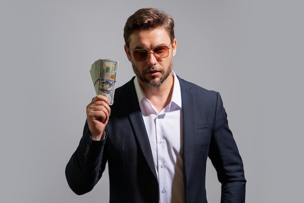Homem de negócios segura dinheiro em estúdio cinza fundo isolado homem rico de terno com notas de dólar