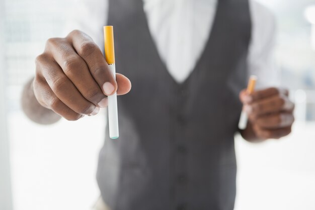 Homem de negócios segurando cigarro eletrônico e cigarro