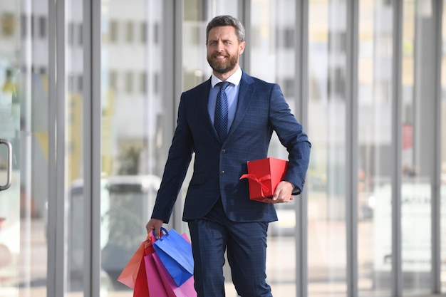 Homem de negócios segurando sacolas de compras e andando na loja de compras. Fazendo compras e pagando. Conceito de compras viciado em compras.