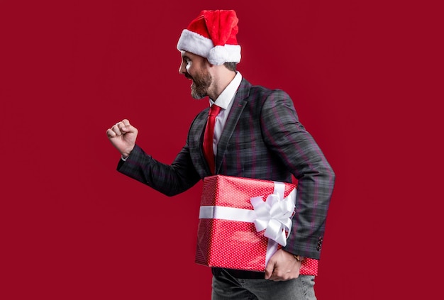 Foto homem de negócios segurar venda de férias presente e apresse-se venda de ano novo homem de negócios segurar presente de ano novo isolado em vermelho venda de ano novo e homem de negócios com presente ano novo homem de negócios santa com presente