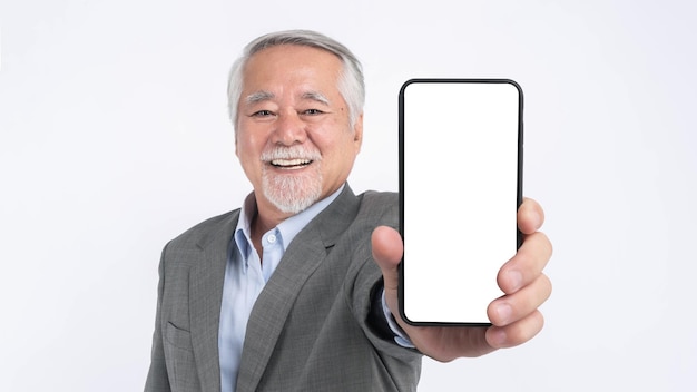 Homem de negócios sênior asiático com terno sente-se feliz com boa saúde mostrando grande telefone inteligente com tela em branco tela branca isolada no fundo branco Mock Up Image