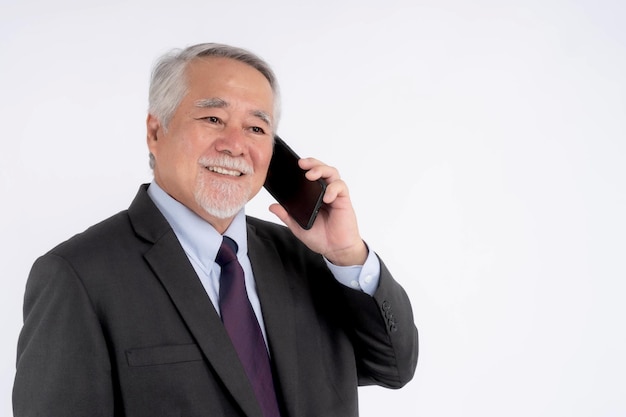 Homem de negócios sênior asiático usando um telefone inteligente sorrindo se sente feliz isolado no conceito de fundo branco para o sucesso empresarial sênior