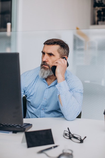 Homem de negócios sênior bonito trabalhando no computador no escritório