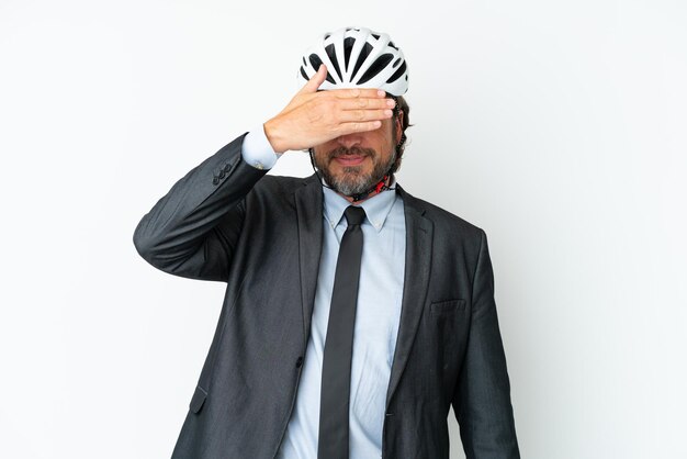 Homem de negócios sênior com um capacete de bicicleta isolado no fundo branco, cobrindo os olhos com as mãos. não quero ver nada