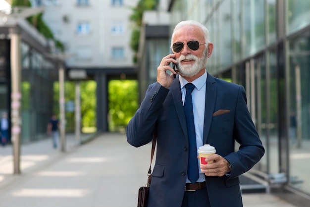 Homem de negócios sênior falando ao telefone com cliente