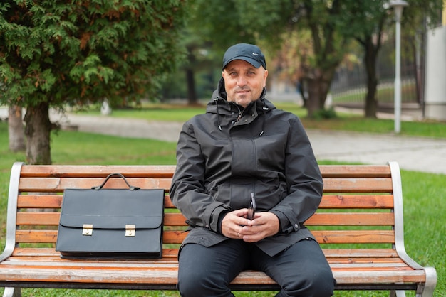 Homem de negócios sênior feliz sentado no banco do parque