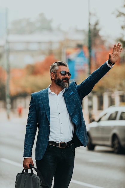 Homem de negócios sênior moderno parando um táxi na cidade.