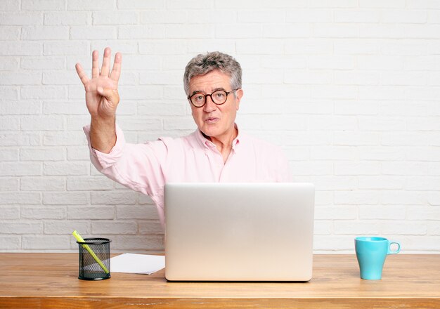 Homem de negócios sênior que sorri e que olha satisfeito e feliz, contando o número quatro com dedos.