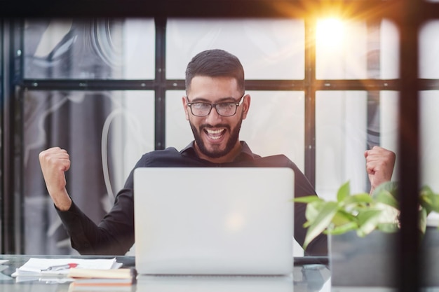 Homem de negócios sentado em sua mesa no escritório com um laptop