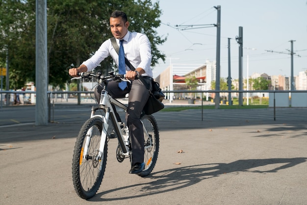 Homem de negócios sério andando de bicicleta