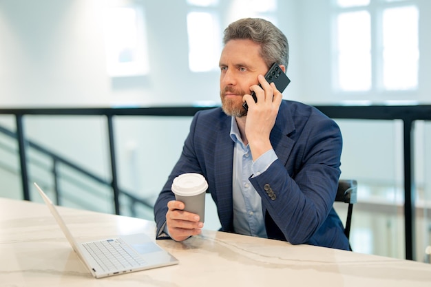 Homem de negócios sério de terno no escritório falando ao telefone Trabalhador de escritório usando o centro de chamadas do escritório