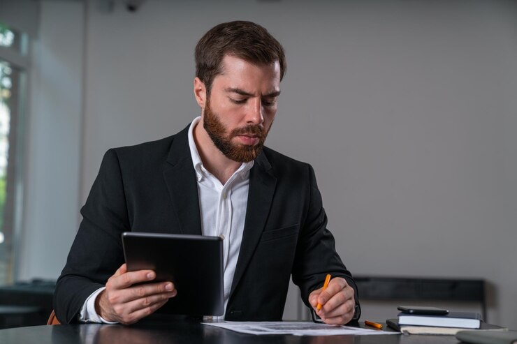 Homem de negócios sério em contrato de assinatura de roupa formal segurando o dispositivo tablet