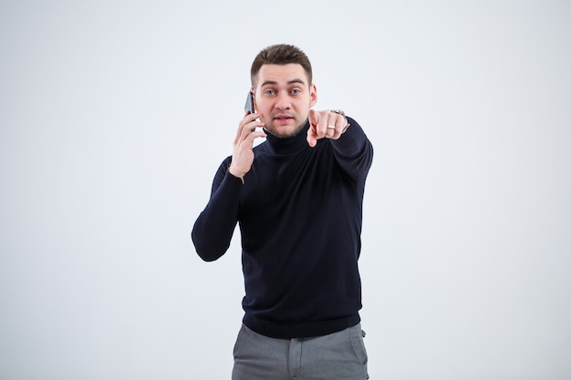 Homem de negócios sério em roupas pretas descobre perguntas importantes por telefone. Conceito de jornada de trabalho