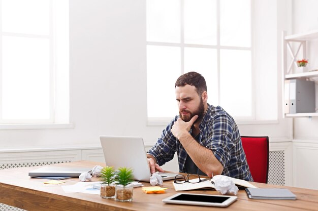 Homem de negócios sério pensativo no escritório. Empregado casual jovem pensativo no trabalho com o computador, o conceito de problemas de trabalho. Retrato de estilo de vida