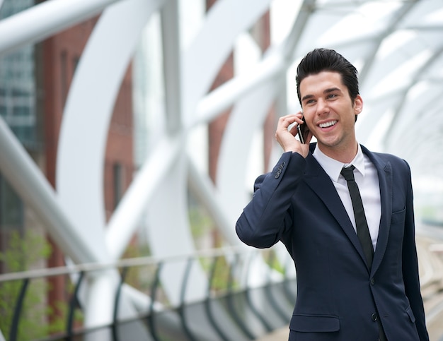 Homem de negócios sorridente, falando no celular na cidade