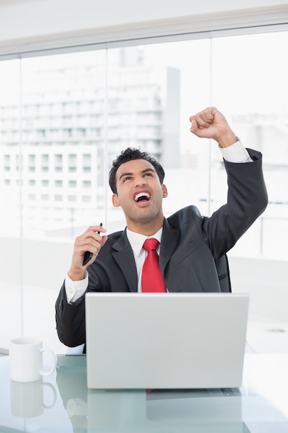 Homem de negócios torcendo na frente do laptop na mesa