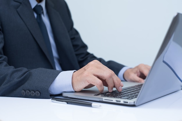 Homem de negócios trabalhando, digitando no teclado do laptop no escritório, close-up