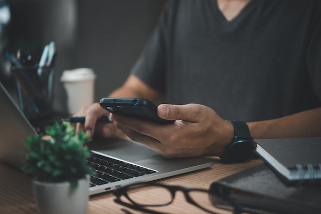 Homem de negócios trabalhando no computador portátil e usando telefone celular no conceito de tecnologia digital de mesa