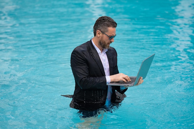 Homem de negócios trabalhando remotamente com foto de computador de homem de negócios trabalhando remotamente na piscina de verão homem de negócios trabalhando remotamente homem de negócios online trabalhando remotamente na piscina