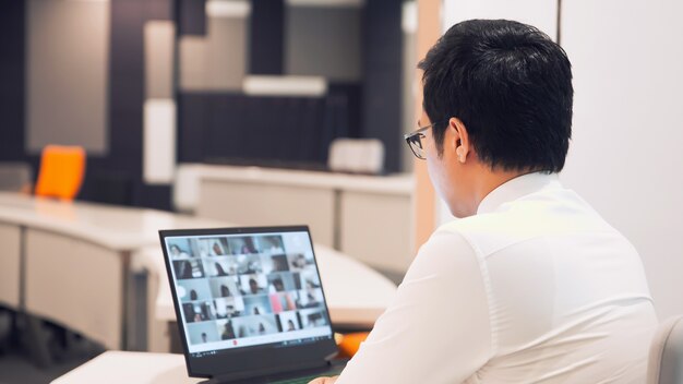 Homem de negócios usa computador para reunião de equipe com programa de videochamada.