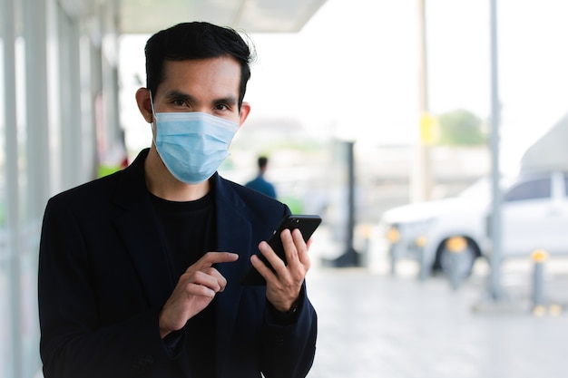 Homem de negócios usa máscara facial, usa smartphone no estilo de vida e depois máscara para proteger o coronavírus covid19