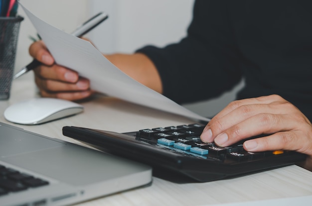 Homem de negócios usando a calculadora em uma mesa. Conceitos de finanças, impostos e investimento de negócios.