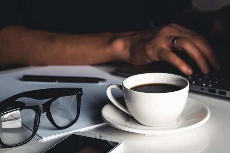 Foto homem de negócios usando computador portátil e digitação manual no teclado do laptop com óculos de caneta de notebook e xícara de café quente